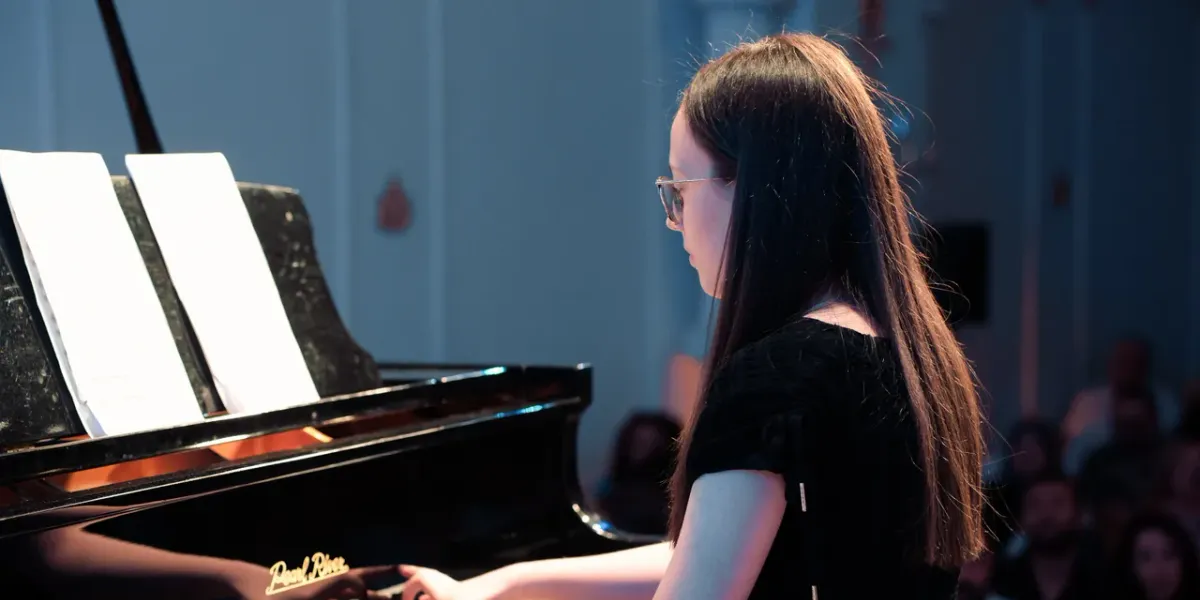 Młoda pianistka grająca na fortepianie podczas recitalu