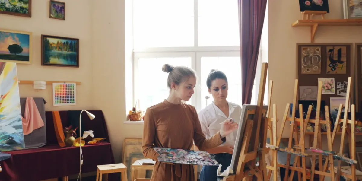 Dwie młode studentki malujące na sztalugach w przestronnej pracowni artystycznej
