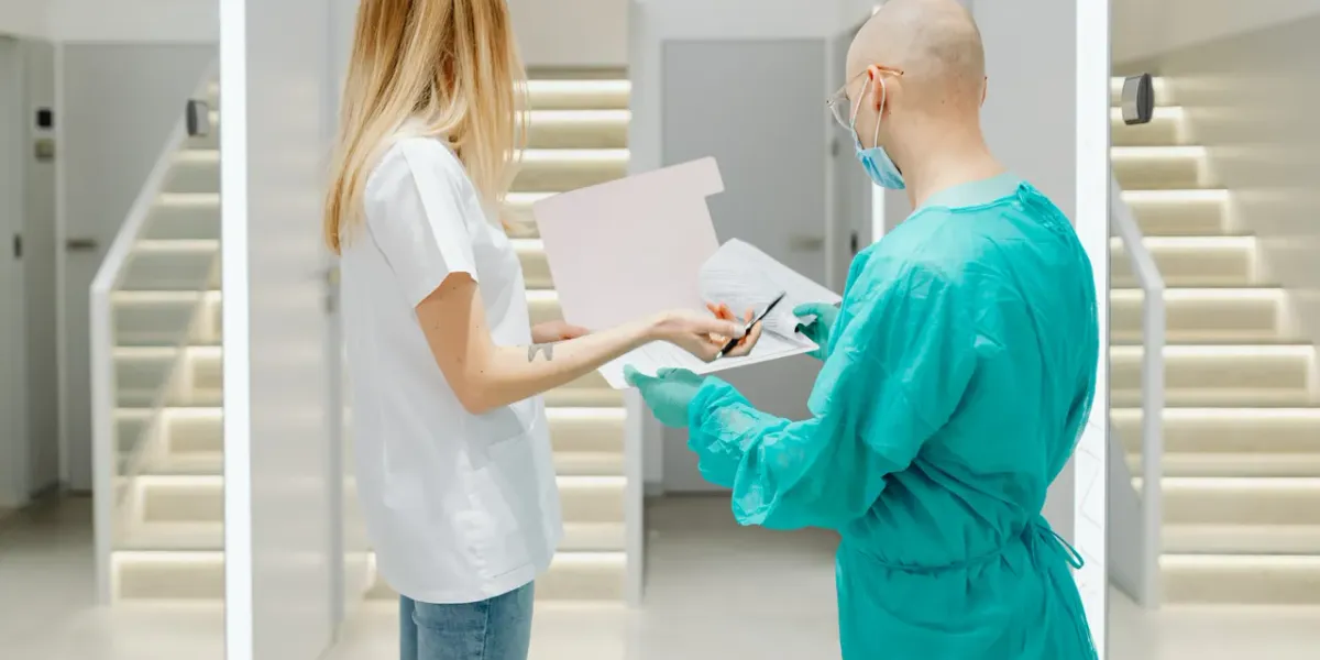 Dwoje pracowników medycznych rozmawiających na szpitalnym korytarzu