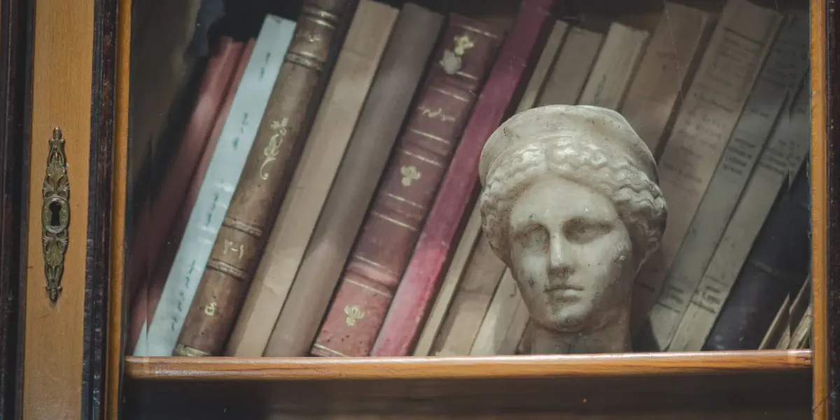 Stare książki i antyczna rzeźba głowy na półce biblioteki