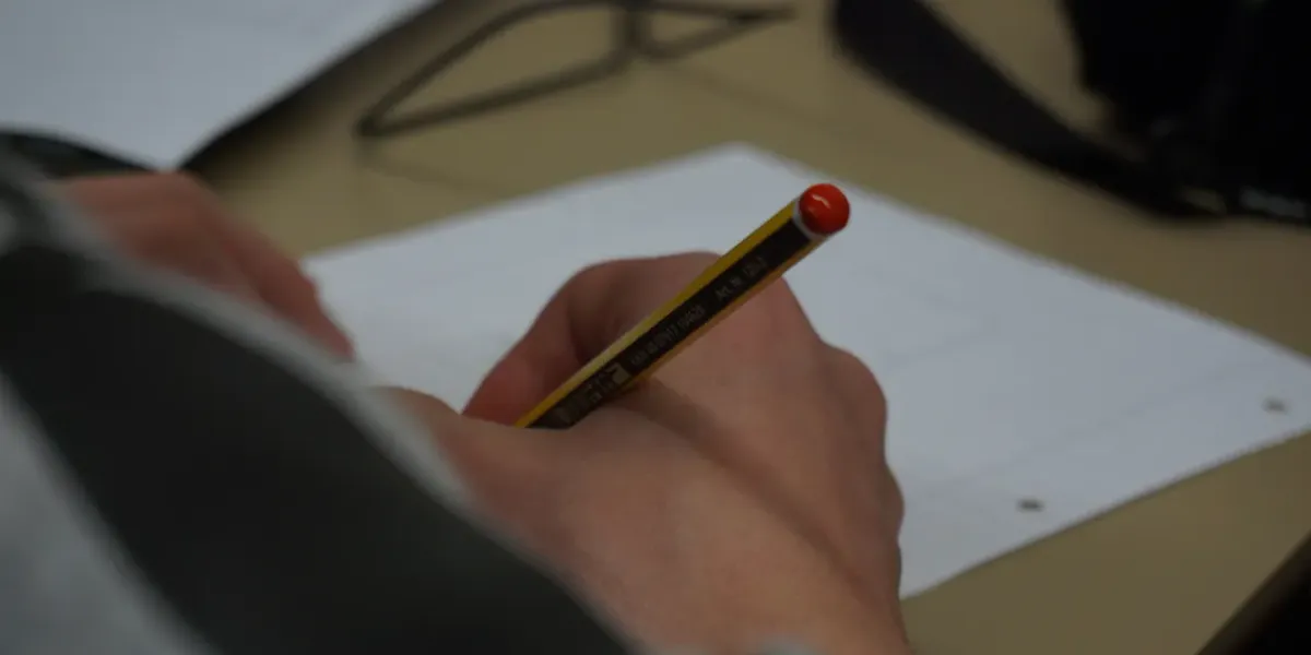 Dłoń piszące ołówkiem na kartce papieru w kratkę