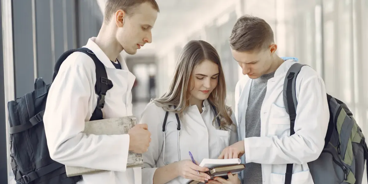 Troje studentów medycyny w białych fartuchach ze stetoskopami