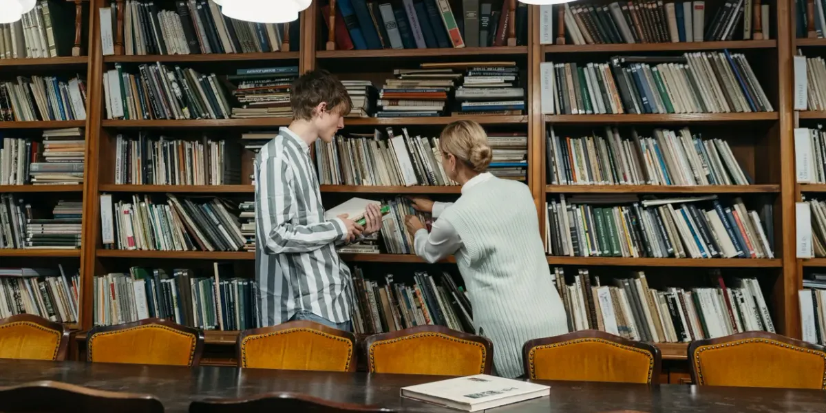 Dwoje studentów przeglądających książki w bibliotece uniwersyteckiej