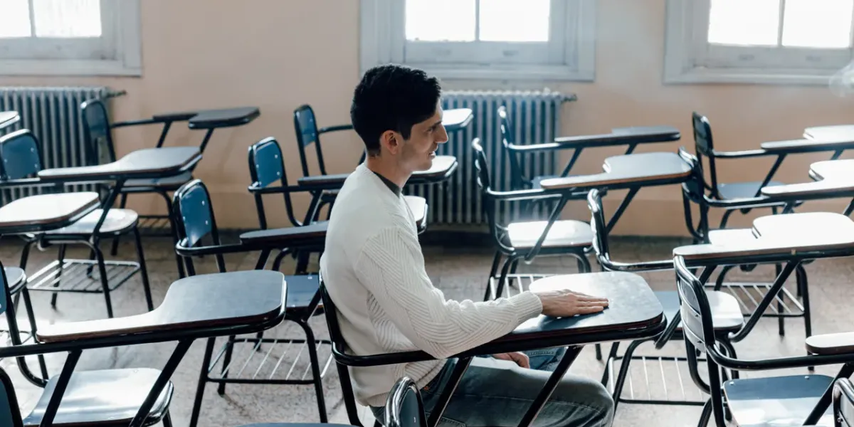 Student siedzący samotnie w pustej sali wykładowej