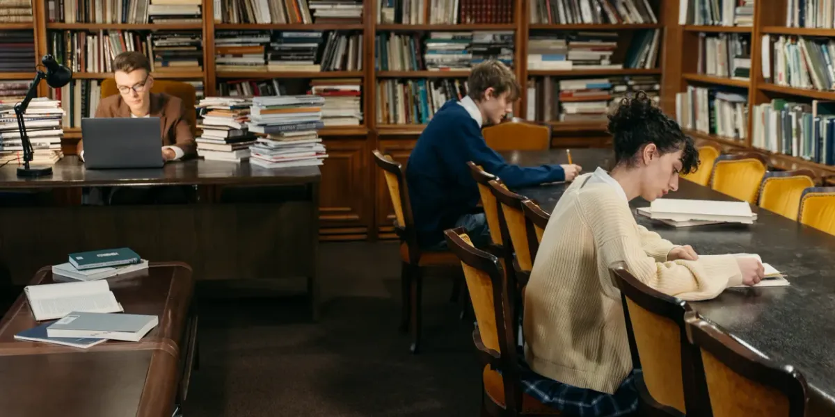 Młodzi ludzie ucząca się przy stole z książkami w bibliotece