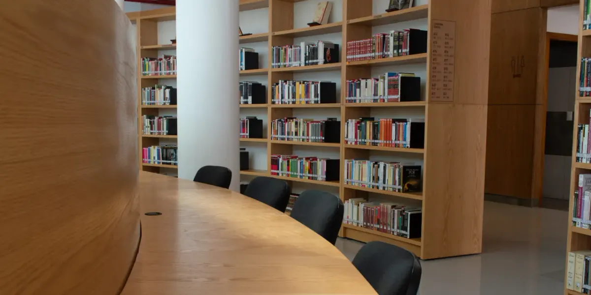 Czytelnia biblioteki uniwersyteckiej z drewnianym stołem i regałami