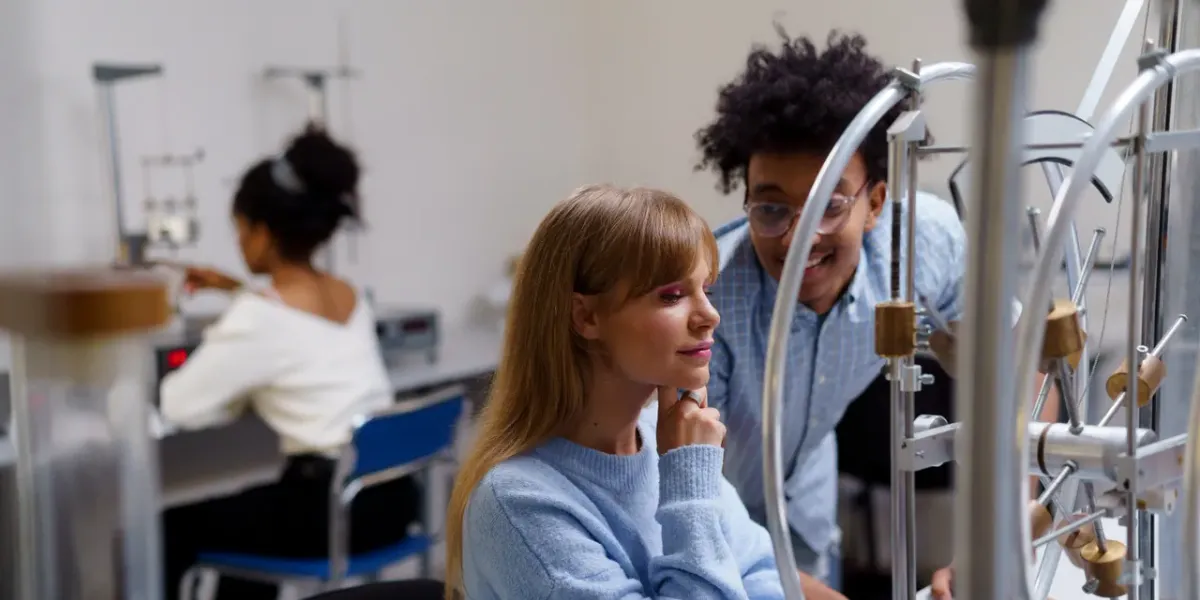 Studentka i student przy urządzeniu laboratoryjnym na uczelni technicznej