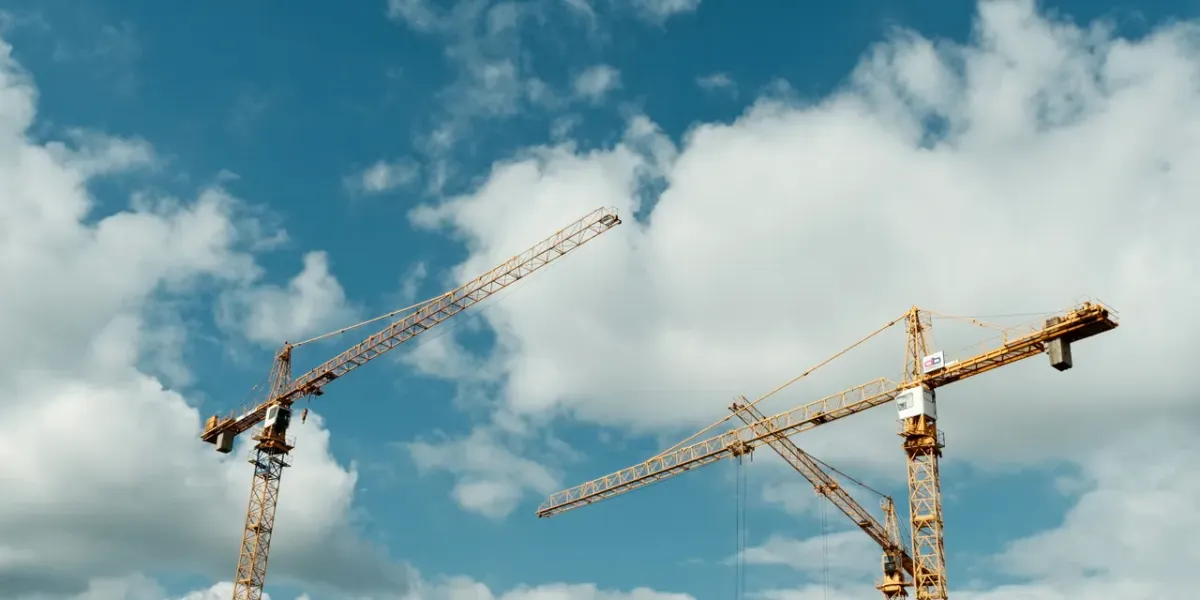 Żurawie budowlane na placu budowy na tle błękitnego nieba
