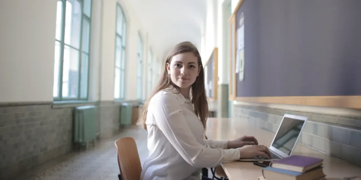 Studentka pracująca na laptopie na korytarzu uczelni