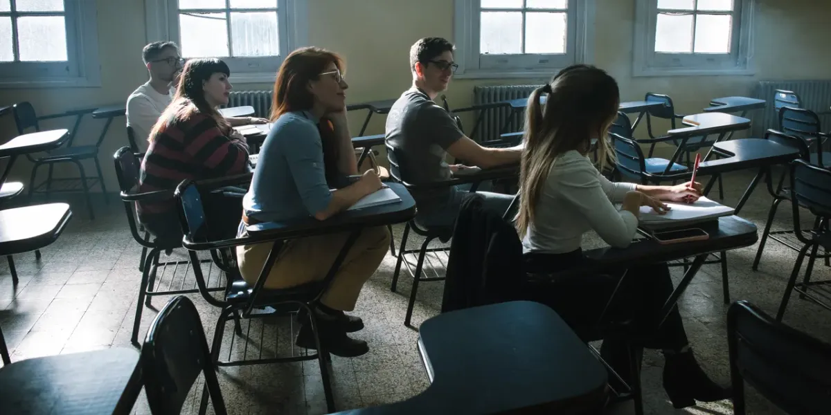 Studenci uważnie słuchający wykładu w sali ze starymi oknami
