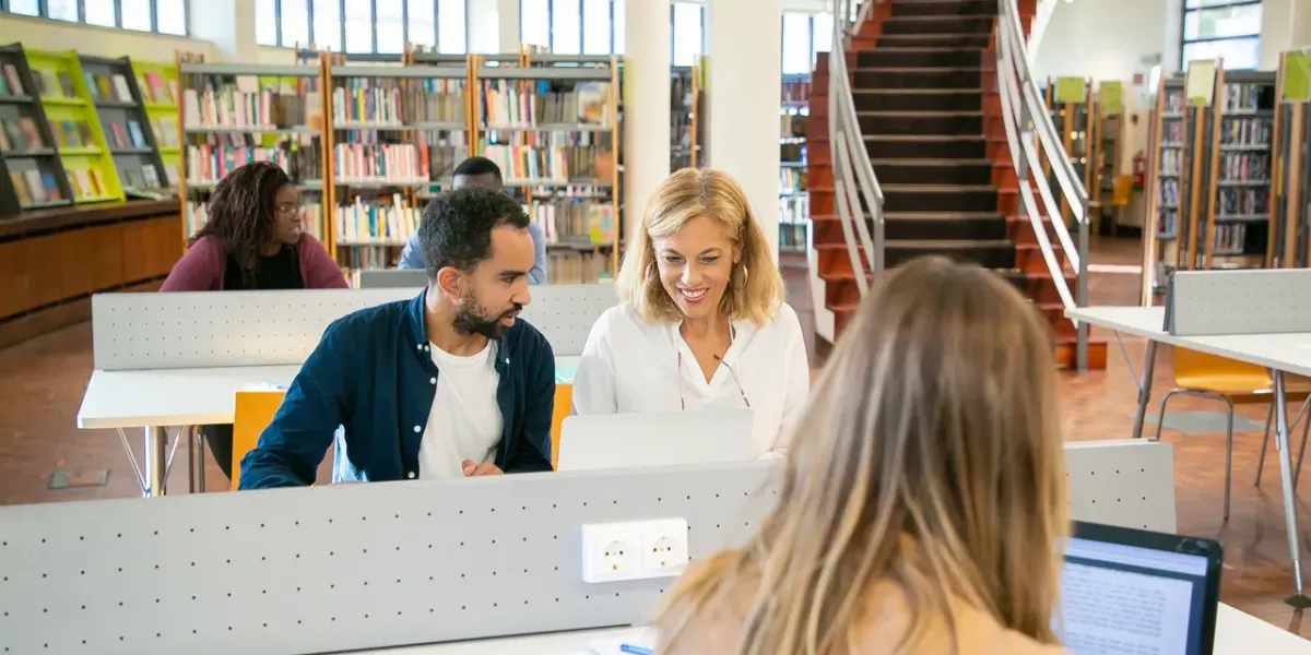Studenci przygotowujący się do egzaminów przy laptopach w bibliotece